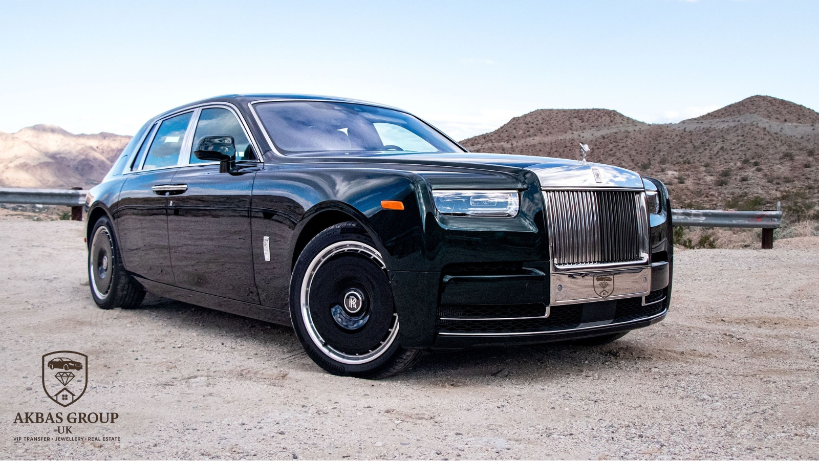 Black luxury car on a desert road with mountains in the background
