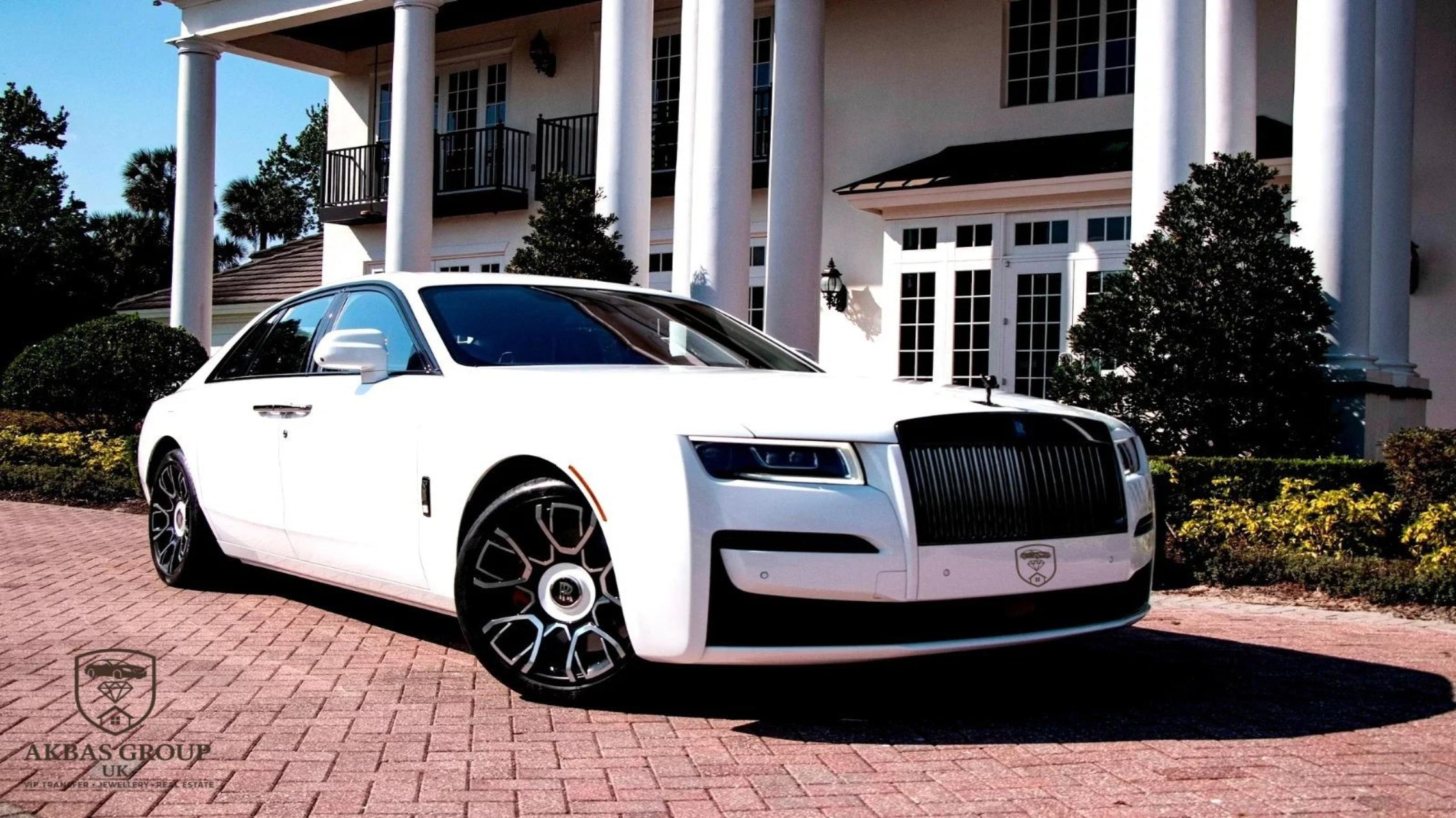 White Rolls-Royce parked in front of a large house with columns